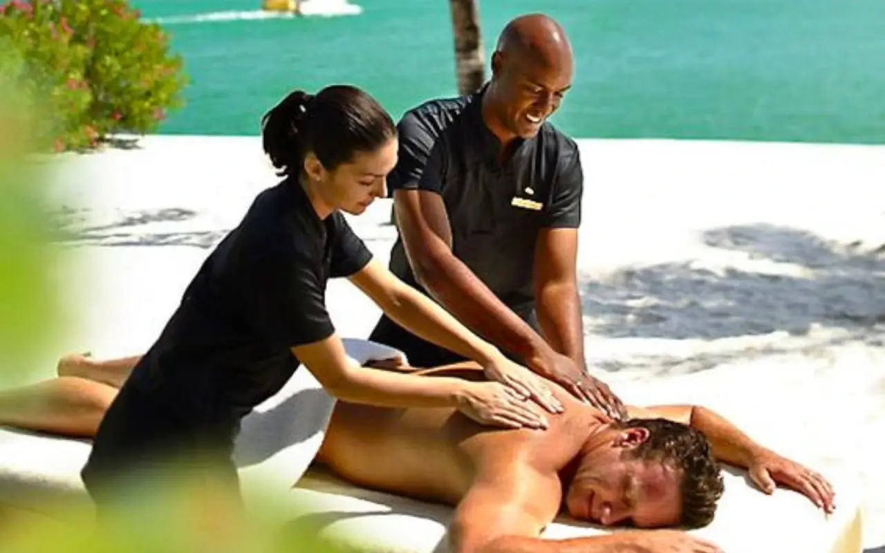 Black-men-and-women-giving-Spa-beach-Massage-to-a-White-guy